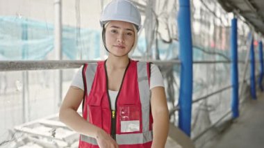 Güzel İspanyol kadın mimar gülümsüyor. Kollarını kavuşturup caddede duruyor.