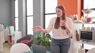 Genç, güzel İspanyol kadın müzik dinliyor ve dans ediyor. Yemek odasında kahve içiyor.