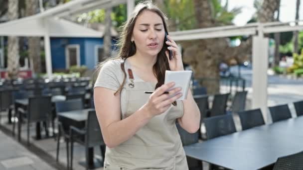 Joven Hermosa Camarera Hispana Hablando Smartphone Leyendo Cuaderno Terraza Cafetería — Vídeos de Stock
