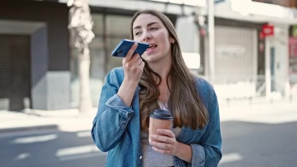年轻美丽的惊慌失措的女人通过智能手机在街上喝咖啡来传达自己的声音 — 图库视频影像