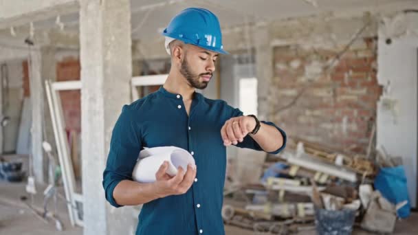 年轻的惊慌失措的建筑师头戴硬帽 拿着设计图 看着建筑工地的腕表 — 图库视频影像