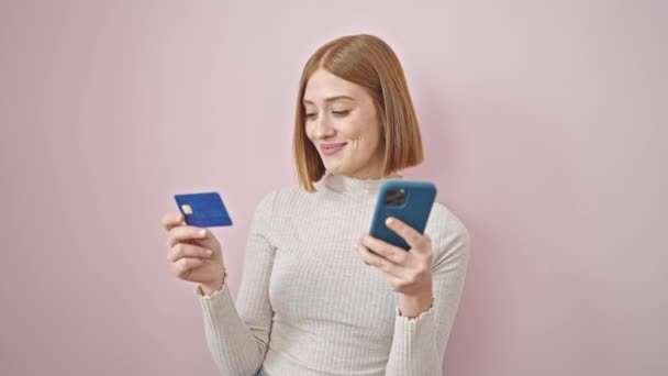 若いですブロンド女性ショッピングとともにスマートフォンやクレジットカード上の隔離されたピンクの背景 — ストック動画