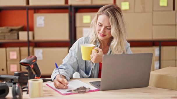 年轻的金发女性电子商务工作者在办公室写关于喝咖啡的文件 — 图库视频影像