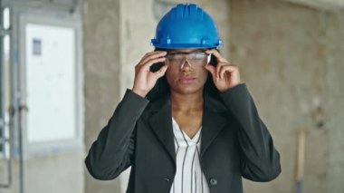 Afro-Amerikan kadın mimar gülümsüyor. İnşaat alanında bardakları çıkarıyor.