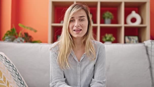 Νεαρή Ξανθιά Γυναίκα Κάθεται Στον Καναπέ Μιλώντας Στο Σπίτι — Αρχείο Βίντεο