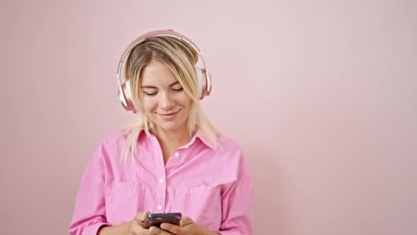 Młoda Blondynka Słuchająca Muzyki Tańczącej Odizolowanym Różowym Tle — Wideo stockowe
