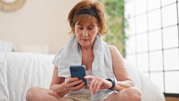 Mulher Meia Idade Sentado Tapete Ioga Usando Smartphone Assistir Quarto — Vídeo de Stock