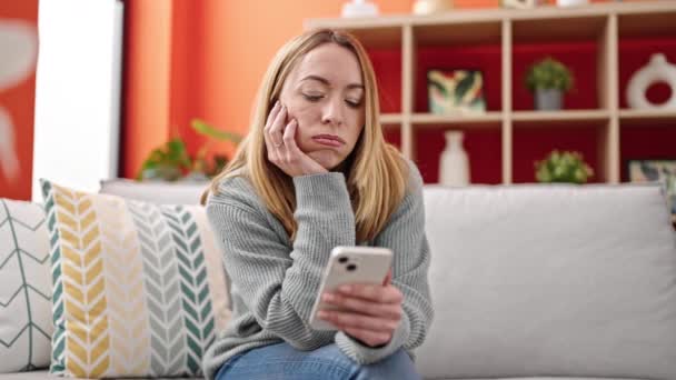 Mladá Blondýna Žena Pomocí Smartphone Sedí Pohovce Hledá Rozrušený Doma — Stock video