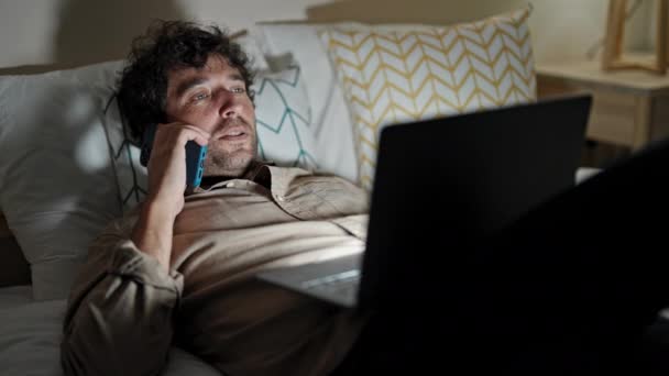 Genç Spanyol Adam Yatak Odasında Laptopunu Kullanarak Akıllı Telefondan Konuşuyor — Stok video