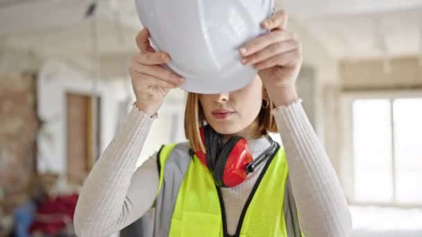 年轻的金发女建筑师站在建筑工地 头戴硬礼帽 表情轻松 — 图库视频影像
