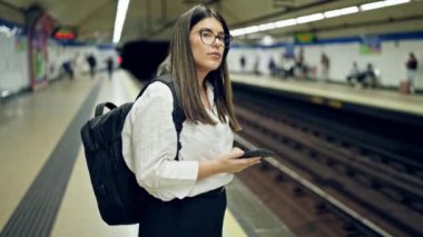 Madrid metro istasyonunda akıllı telefon kullanan güzel İspanyol bir kadın metroda bekliyor.