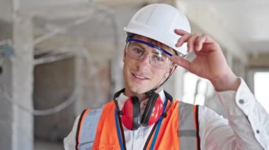 Kafkasyalı genç mimar inşaat alanında kendine güvenerek gülümsüyor.