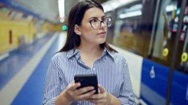 Madrid metro istasyonunda akıllı telefon kullanan güzel İspanyol bir kadın metroda bekliyor.