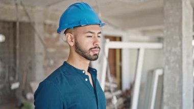 İnşaat alanında gülümseyen şapkalı genç İspanyol mimar.