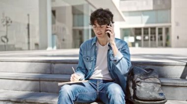 Genç İspanyol öğrenci, üniversitede akıllı telefon ile not defteriyle konuşuyor.