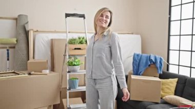 Young blonde woman smiling confident standing at new home