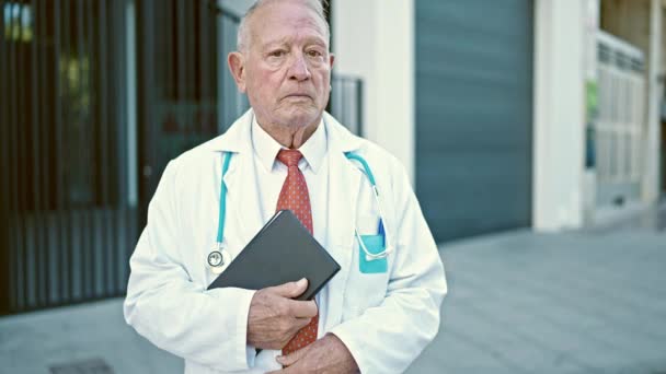 Starszy Siwowłosy Lekarz Stojący Poważnym Wyrazem Twarzy Trzymający Touchpad Ulicy — Wideo stockowe
