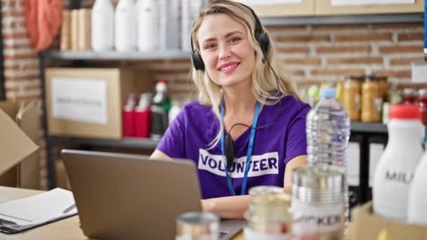 Молода Блондинка Волонтерка Використовує Ноутбук Навушники Посміхається Благодійному Центрі — стокове відео