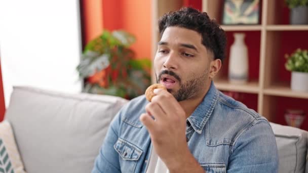 Hombre Afroamericano Sentado Sofá Comiendo Donut Casa — Vídeos de Stock
