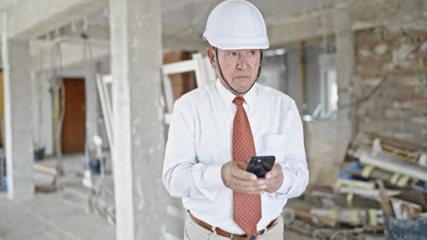 Senior Γκριζομάλλης Αρχιτέκτονας Άνθρωπος Χρησιμοποιώντας Smartphone Κοιτάζοντας Γύρω Στο Εργοτάξιο — Αρχείο Βίντεο
