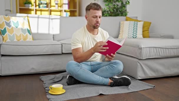 Junger Mann Trinkt Hause Kaffee Und Liest Buch — Stockvideo