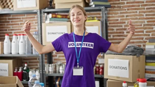 Jovem Loira Apontando Para Uniforme Voluntário Sorrindo Centro Caridade — Vídeo de Stock