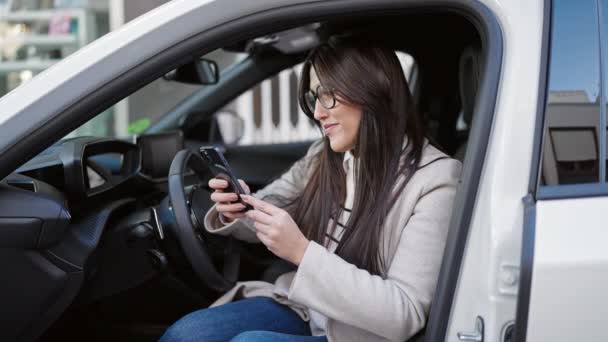 Young Beautiful Hispanic Woman Using Smartphone Sitting Car Street — ストック動画