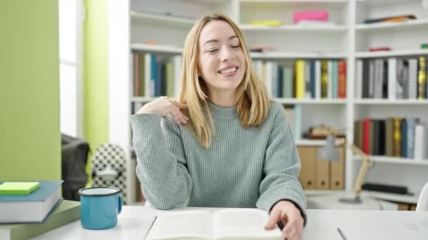 若いですブロンド女性学生読書本でライブラリ大学で話す — ストック動画