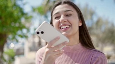 Genç, güzel İspanyol kadın parkta akıllı telefonuyla sesli mesaj yolluyor.