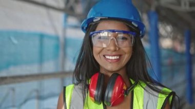 Afro-Amerikalı kadın inşaatçı gülümseyerek sokakta duruyor.