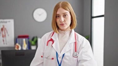 Genç sarışın kadın doktor klinikte başparmağını kaldırıyor.