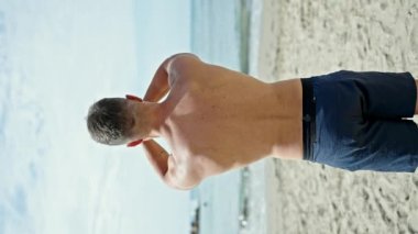 Genç adam plajda yoga eğitimi veriyor.