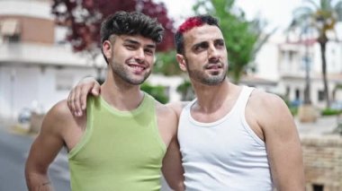 Two men couple smiling confident hugging each other at street