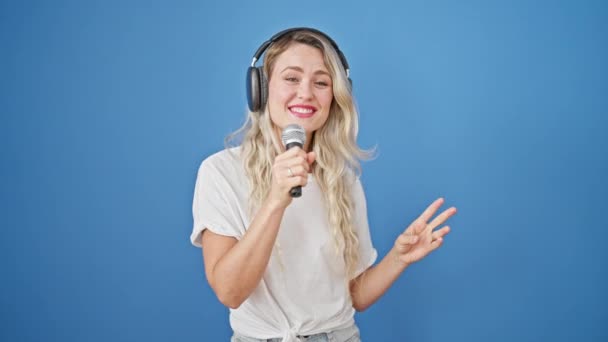 Jong Blond Vrouw Luisteren Naar Muziek Zingen Lied Geïsoleerde Blauw — Stockvideo