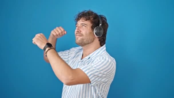Joven Hispano Escuchando Música Bailando Sobre Fondo Azul Aislado — Vídeo de stock