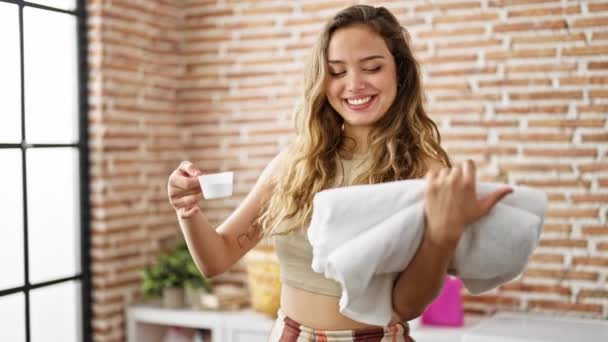 Jonge Mooie Spaanse Vrouw Glimlachend Zelfverzekerd Vasthouden Gevouwen Handdoeken Wasmiddel — Stockvideo