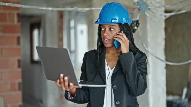 African American Woman Architect Using Laptop Talking Smartphone Construction Site — Stock Video