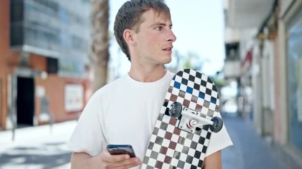 Young Caucasian Man Using Smartphone Holding Skate Street — Stock Video