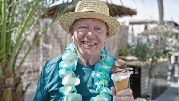 シニア白髪の男性観光客は夏の帽子をかぶっていて ハワイのレイは通りでアイスクリームを持っています — ストック動画