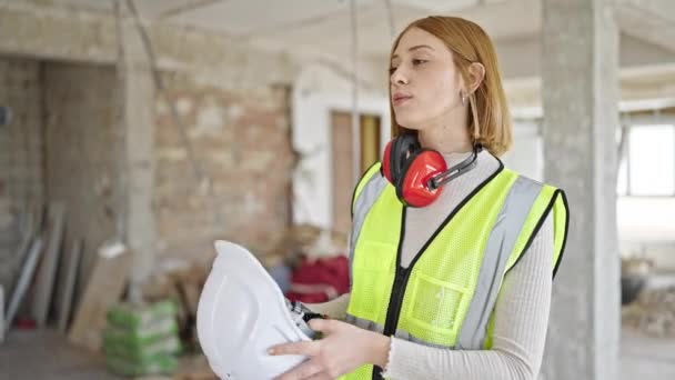 年轻的金发女建筑师在建筑工地用硬礼帽作为手扇 — 图库视频影像