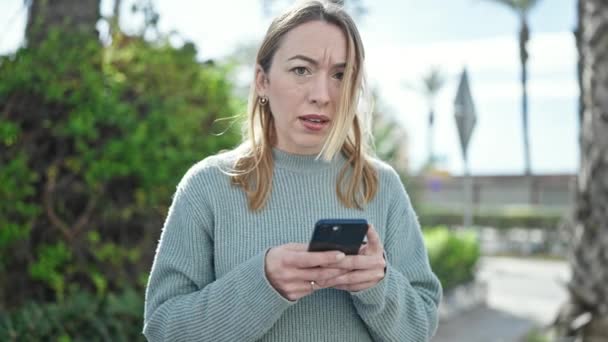 Jonge Blonde Vrouw Met Smartphone Met Serieuze Expressie Het Park — Stockvideo