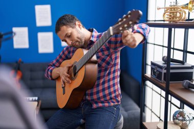 Young man musician playing classical guitar at music studio