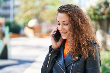 Genç, güzel İspanyol kadın gülümsüyor. Parktaki akıllı telefondan konuşuyor.