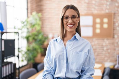 Genç, güzel, İspanyol bir iş kadını. Ofiste kendinden emin bir şekilde gülümsüyor.