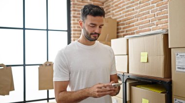 Ofisteki akıllı telefonu kullanan Latin asıllı genç bir iş adamı.