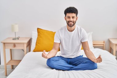 Genç Arap, yoga egzersizi yapıyor. Yatak odasında oturuyor.