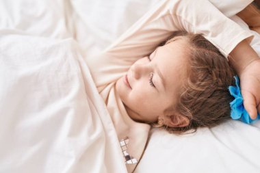 Adorable caucasian girl lying on bed sleeping at bedroom