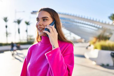 Parktaki akıllı telefondan konuşan, kendine güvenen genç bir kadın.