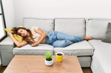 Young beautiful hispanic woman lying on sofa sleeping at home