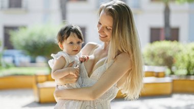 Anne ve kızı parkta birbirlerine gülümsüyorlar.